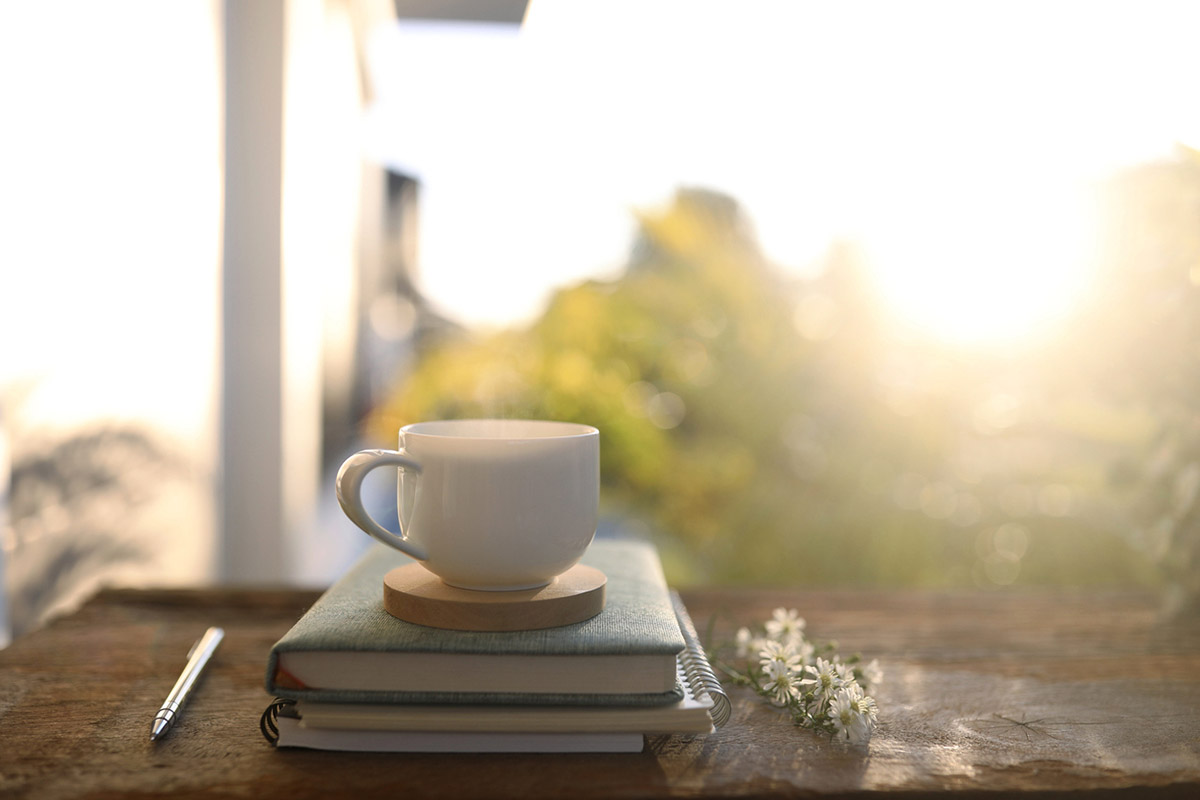 Soft daylight across an uncluttered desk with a notebook and a glass of water, suggesting breathing room in a workday